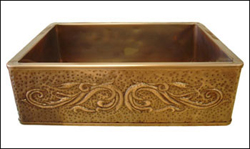 copper farmhouse sink with a repoussé apron front and a hammered texture fill